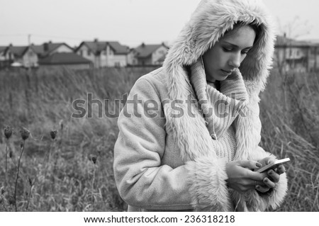 woman using smartphone in fields behind country town