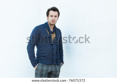 fashionable man in cardigan near the wall