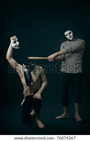 two angry mimes fighting in studio. one of them tries to kick the head off with the bat