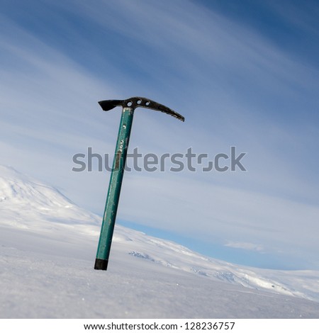 Ice axe with snow-capped mountain in the background