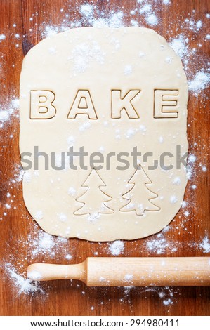Dough with letters and rolling pin on the wooden table. Kitchen background