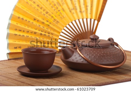 Ceramic teapot with a cup of tea on white background