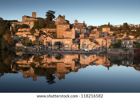 Reflected french village, Puy l\'Eveque, at sunset in the Lot River, France