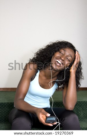 Young African American Female Sitting Down Listening to Music Player