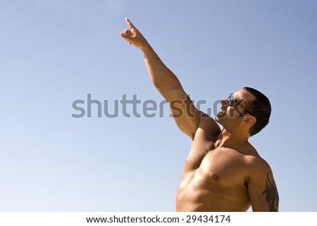 Young Muscular Male Pointing at Sky with Blue Background