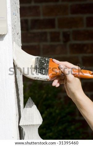 Woman Making Home Improvements By Painting House