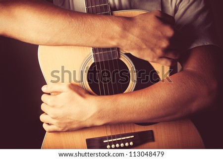 hands holding an acoustic guitar