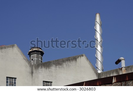 Two Industrial Chimneys On An Industrial Factory Roof, Facade, Clear Blue Sky