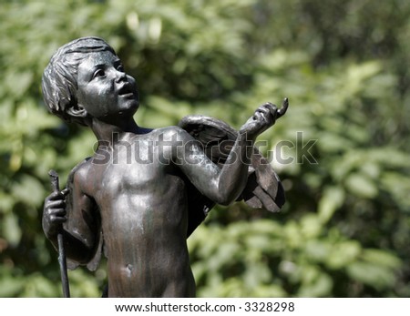 Young Angel Statue, Dark Metal Sculpture In Front Of Green Plants, Sydney Public Park