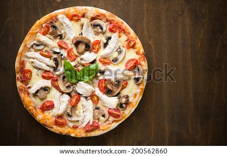 Pizza with chicken and mushrooms on dark wooden background top view