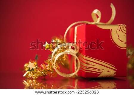 Red gift box with golden ribbons on red background. Merry christmas.