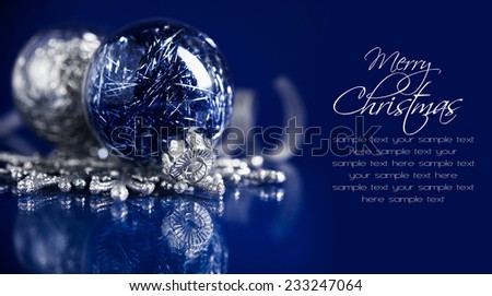 Silver and blue christmas ornaments on dark blue background with space for text. Sample text on solid color, easy to delete. Merry christmas card. Winter holidays. Xmas theme.
