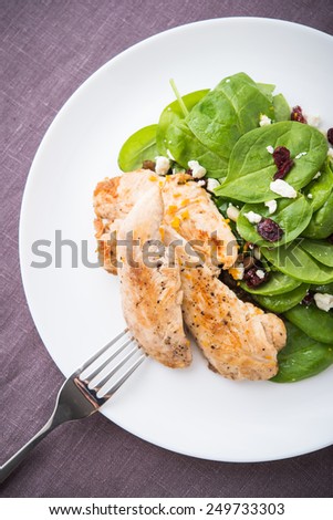 Chicken with spinach salad on dark background top view. Healthy food.