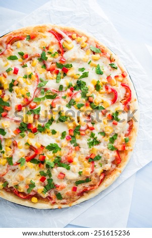 Pizza with mozzarella cheese, chicken, sweet corn, sweet pepper and parsley top view. Italian cuisine.