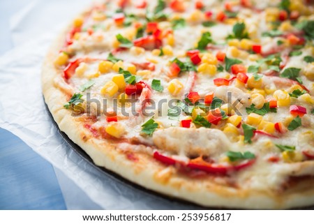 Pizza with mozzarella cheese, chicken, sweet corn, sweet pepper and parsley close up. Italian cuisine.