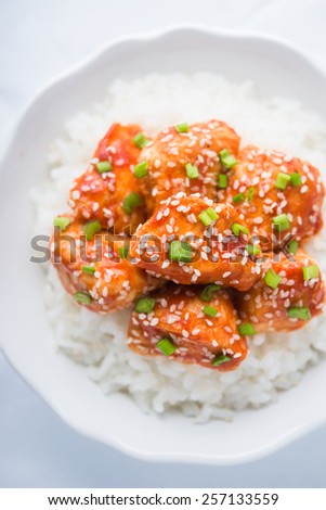 Spicy sweet and sour chicken with sesame and rice top view. Oriental food.