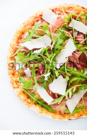 Pizza with prosciutto (parma ham), arugula (salad rocket) and parmesan top view. Italian cuisine.