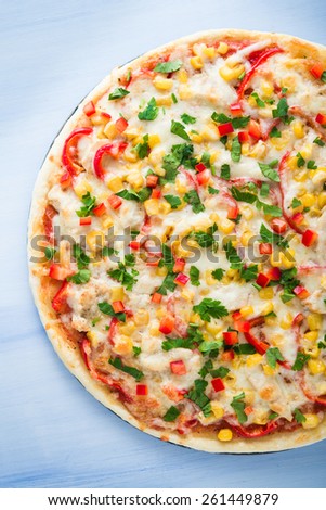 Pizza with mozzarella cheese, chicken, sweet corn, sweet pepper and parsley on blue wooden background top view. Italian cuisine.