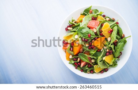 Fresh salad with fruits and greens on blue wooden background top view. Healthy food. Space for text.