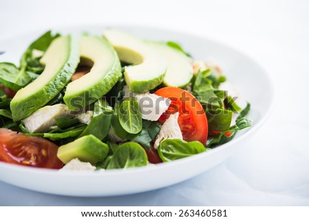 Fresh salad with chicken, tomatoes, spinach and avocado on white background close up. Healthy food.