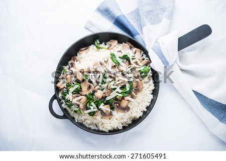 Rice (risotto) with mushrooms, parmesan and spinach top view on white background. Italian cuisine.