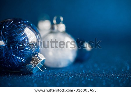 White and silver christmas ornaments on dark blue glitter background with space for text. Merry christmas card. Winter holidays. Xmas.