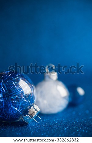 White and silver christmas ornaments on dark blue glitter background with space for text. Merry christmas card. Winter holidays. Xmas theme.