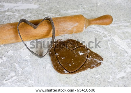 Gingerbread dough,heart cookie cutter and rolling pin on floured counter top