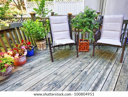 Chairs and plants on wooden deck in backyard of home