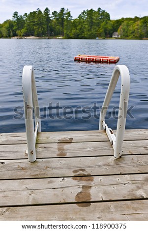 Wet footprints on dock with ladder and diving platform at lake in Ontario Canada