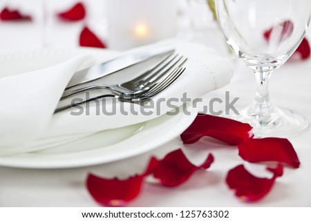 Romantic table setting with rose petals plates and cutlery