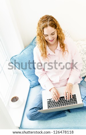Caucasian woman using laptop computer sitting on couch at home