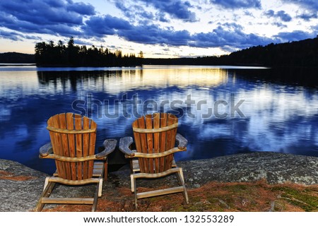 Landscape with adirondack chairs on shore of relaxing lake at sunset in Algonquin Park, Canada