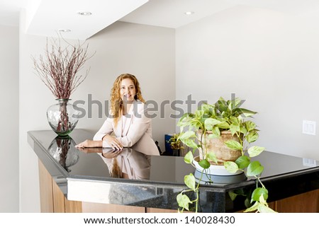Receptionist standing at reception counter in office