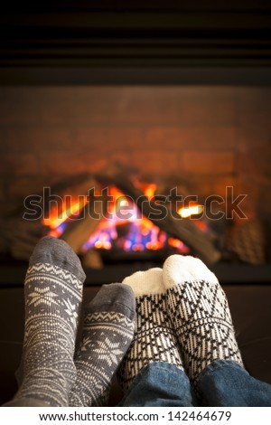 Feet in wool socks warming by cozy fire