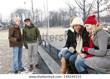 Two young men looking at three pretty women in winter park