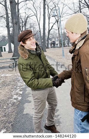 Two young men meeting in winter park shaking hands
