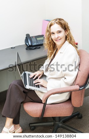 Confident businesswoman sitting at workstation in office with computer