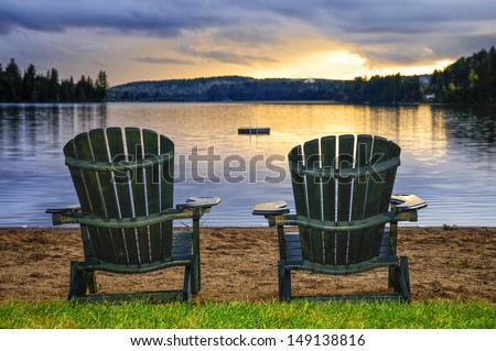Two wooden chairs on beach of relaxing lake at sunset. Algonquin provincial park, Canada.