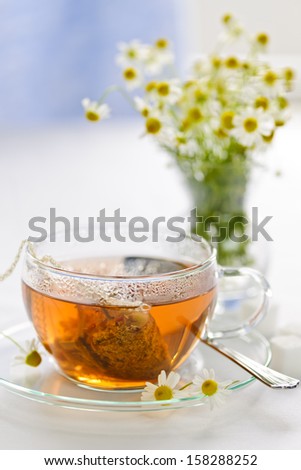 Glass teacup with soothing herbal tea in silk bag