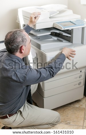 Business man opening photocopy machine in office
