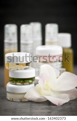 Various jars and bottles of skin care products with orchid flower