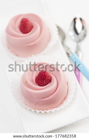 Two pink raspberry mousse desserts on a plate