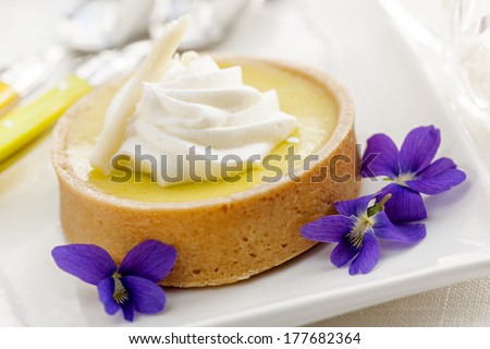 Fresh gourmet lemon dessert tart with edible violet flowers garnish