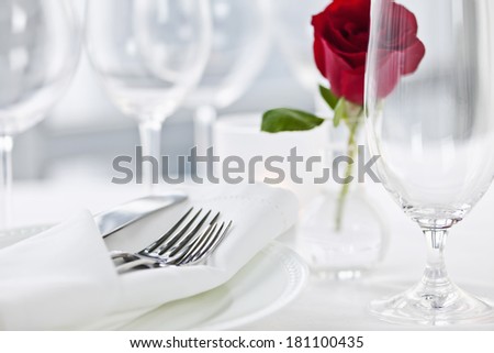 Romantic restaurant table setting with rose candle plates and cutlery