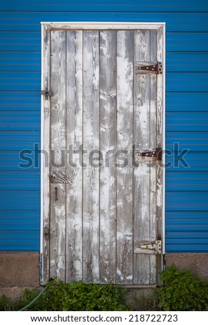 Old weathered wooden door on side of blue building. Prince Edward Island, Canada.