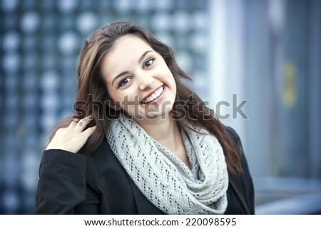 Candid portrait of young brunette woman smiling and touching her hair with copy space