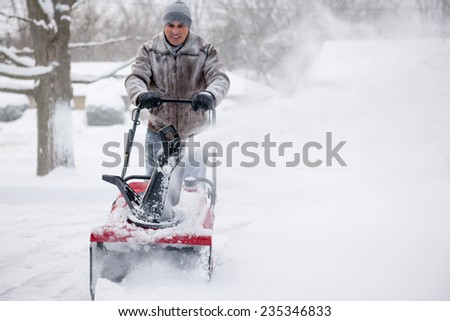 Man using snowblower to clear deep snow on residential driveway after heavy snowfall