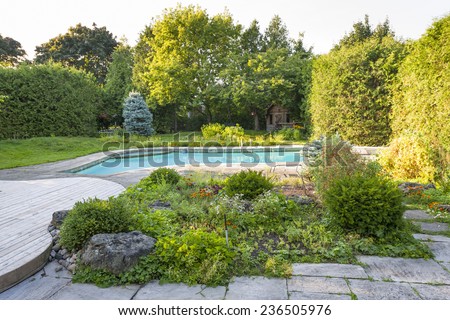 Backyard rock garden with outdoor inground residential private swimming pool and stone patio