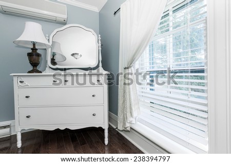 White painted dresser with mirror and lamp near window interior